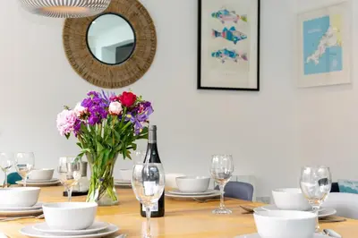 a dining room table with a bottle of wine and flowers at 5 Bed in Padstow oc-p00628 in Padstow