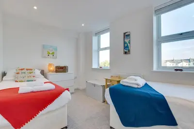 a bedroom with two beds and a desk and windows at 3 Bed in Newquay oc-p00631 in Newquay