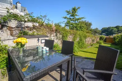 a table and two chairs on a patio with a table and flowers at 2 Bed in Padstow oc-p00632 in Padstow