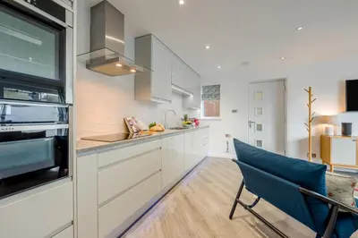 a kitchen with white cabinets and a blue chair at 2 Bed in Padstow oc-p00655 in Padstow