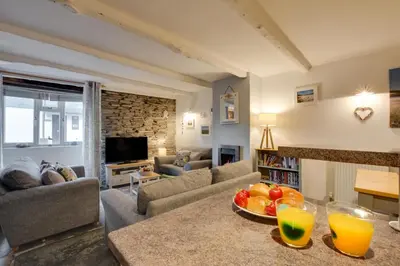 a living room with a table with two glasses of orange juice at 2 Bed in Padstow oc-p00670 in Padstow