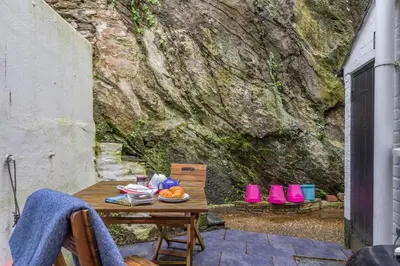 a table with a bowl of fruit on it next to a stone wall at 2 Bed in Fowey oc-p00671 in Fowey