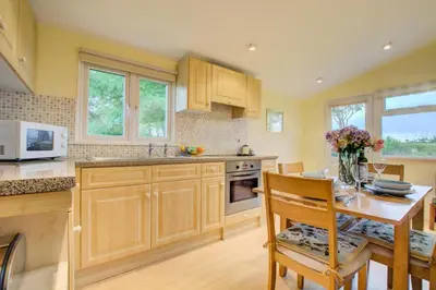 a kitchen with wooden cabinets and a table with flowers on it at 2 Bed in St. Merryn oc-p00673 in St Merryn