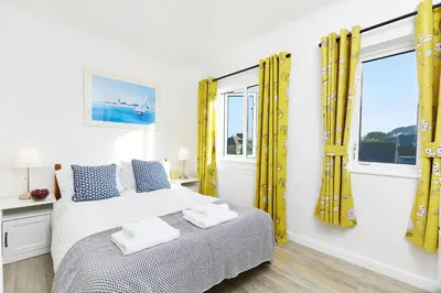 a bedroom with yellow curtains and a bed with towels on it at 2 Bed in St. Ives oc-p00693 in Carbis Bay