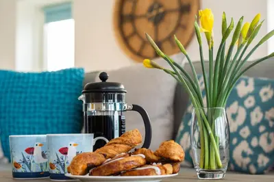 a table with a plate of pastries and a vase with flowers at 3 Bed in Perranporth oc-p00695 in Perranporth