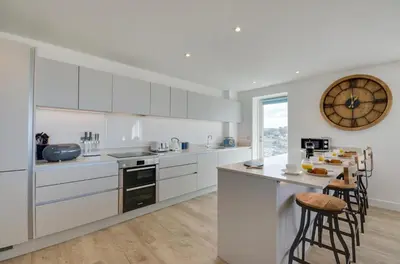 a kitchen with white cabinets and a counter with stools at 3 Bed in Perranporth oc-p00695 in Perranporth