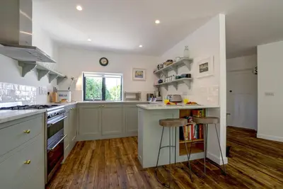 a large kitchen with white cabinets and wooden floors at 4 Bed in Trevone oc-p00696 in Padstow