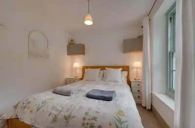 a bedroom with a bed and two lamps and a window at 2 Bed in Polruan oc-p00697 in Fowey