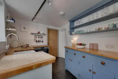 a large kitchen with blue cabinets and a sink at 2 Bed in Polruan oc-p00697 in Fowey