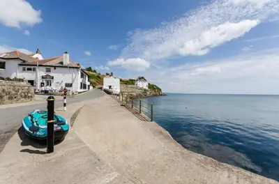 a boat sitting on a sidewalk next to the water at 5 Bed in Mevagissey oc-p00699 in Mevagissey