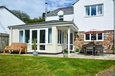 a house with a patio with a bench and an umbrella at 5 Bed in Mevagissey oc-p00699 in Mevagissey