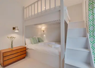 a white bedroom with a bunk bed and a wooden table at 2 Bed in Fowey oc-p00703 in Fowey
