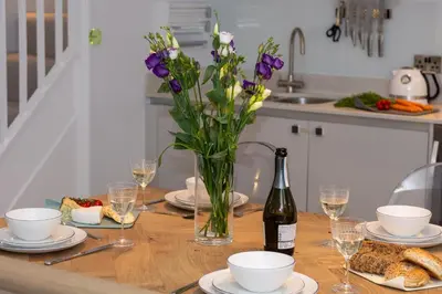 a table with a vase of flowers and a bottle of wine at 2 Bed in Fowey oc-p00703 in Fowey
