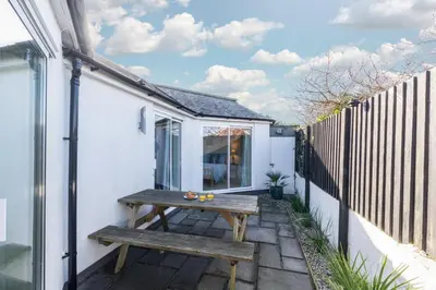a wooden picnic table on the side of a white house at 3 Bed in Trevone oc-p00723 in Padstow
