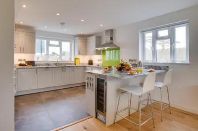 a kitchen with white cabinets and a island with bar stools at 3 Bed in St. Merryn oc-p00725 in St Merryn
