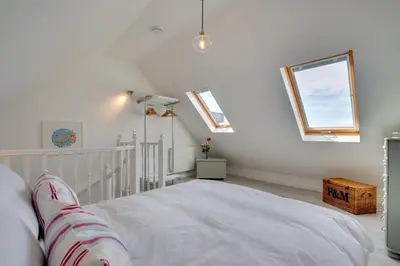 a bedroom with white walls and a bed with windows at 1 Bed in Padstow oc-p00730 in Padstow