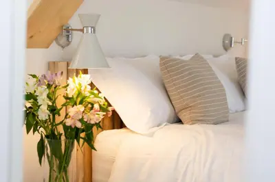 a vase of flowers sitting next to a bed at 5 Bed in Little Petherick oc-p00736 in Little Petherick