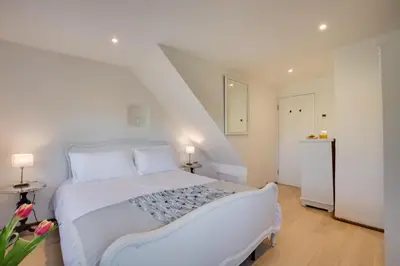 a white bedroom with a white bed and a staircase at 5 Bed in Little Petherick oc-p00736 in Little Petherick