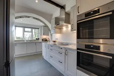 a kitchen with white cabinets and stainless steel appliances at 5 Bed in Little Petherick oc-p00736 in Little Petherick