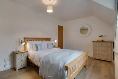 a white bedroom with a large bed and two dressers at 3 Bed in Padstow oc-p00742 in Padstow