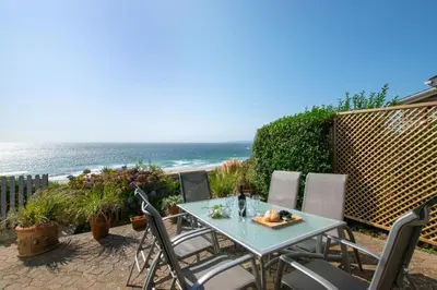 a table and chairs with the ocean in the background at 3 Bed in Praa Sands oc-p00859 in Praa Sands