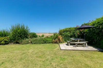 a picnic table and an umbrella in a yard at 4 Bed in Trevone oc-p00863 in Padstow
