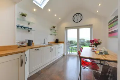 a kitchen with a table and a clock on the wall at 4 Bed in Trevone oc-p00863 in Padstow