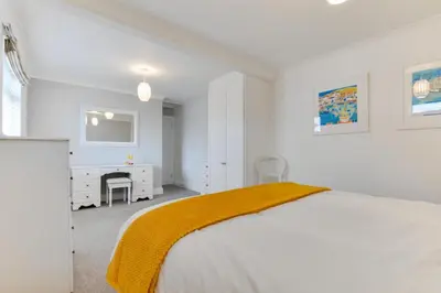 a white bedroom with a bed and a desk at 4 Bed in Trevone oc-p00863 in Padstow