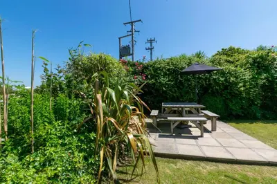 a picnic table with an umbrella in a garden at 4 Bed in Trevone oc-p00863 in Padstow