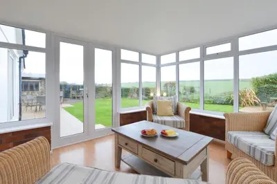 a living room with a table and chairs and windows at 4 Bed in Trevone oc-p00863 in Padstow