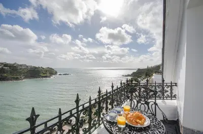 a table with oranges on a balcony with a view of the ocean at 2 Bed in Fowey oc-p00873 in Fowey