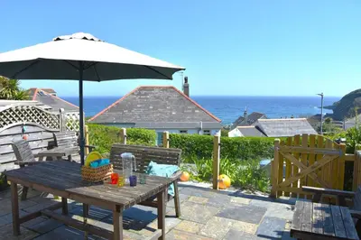 a table and chairs with an umbrella and the ocean at 3 Bed in Gorran Haven oc-p00812 in Gorran Haven