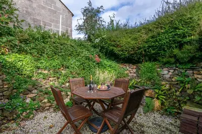 a wooden table with two chairs next to a wall at 2 Bed in Talskiddy oc-p00844 in Saint Columb Major