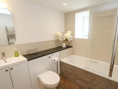 a bathroom with a toilet and a tub and a sink at Gilly Skyber in Helston