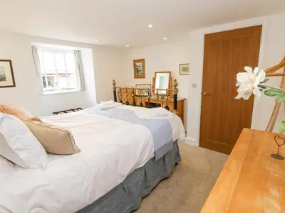 a bedroom with two beds and a wooden table at Gilly Skyber in Helston
