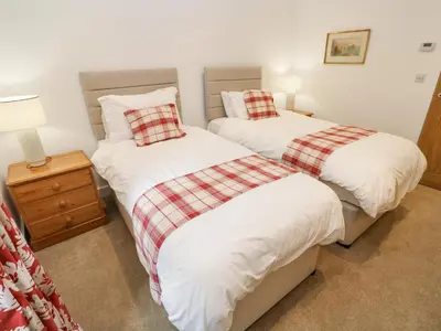 a bedroom with two beds and a night stand at Gilly Skyber in Helston