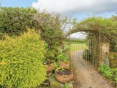 a garden with an archway and potted plants at Gilly Skyber in Helston