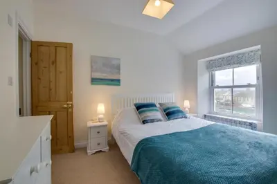 a bedroom with a bed with blue pillows and a window at 2 Bed in Porthleven oc-pevcot in Porthleven