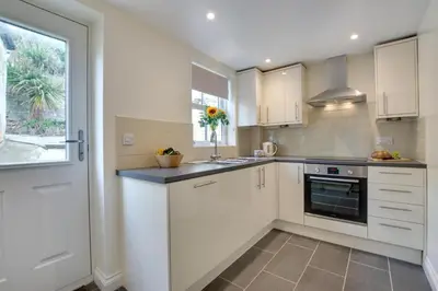 a kitchen with white cabinets and a window at 2 Bed in Porthleven oc-pevcot in Porthleven