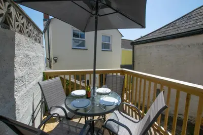 a table and chairs on a balcony with an umbrella at 2 Bed in Porthleven oc-pevcot in Porthleven