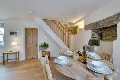 a dining room with a wooden table and a staircase at 2 Bed in Porthleven oc-pevcot in Porthleven