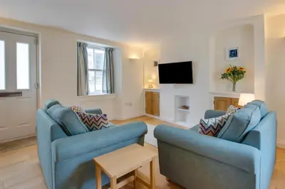 a living room with two blue chairs and a tv at 2 Bed in Porthleven oc-pevcot in Porthleven