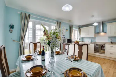 a dining room table with a vase of flowers on it at 3 Bed in Portreath oc-pc054 in Portreath