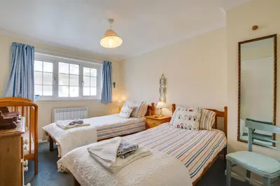 a bedroom with two beds and a chair in it at 3 Bed in Portreath oc-pc054 in Portreath
