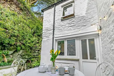 a table with flowers on it in front of a building at 2 Bed in Wadebridge oc-r27444 in Little Petherick