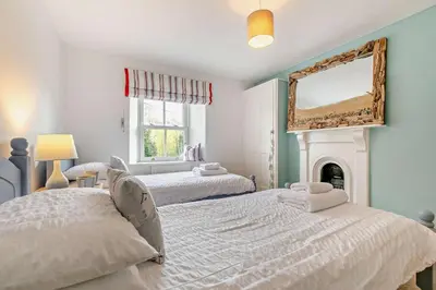 a bedroom with two beds and a mirror on the wall at 2 Bed in Wadebridge oc-r27444 in Little Petherick