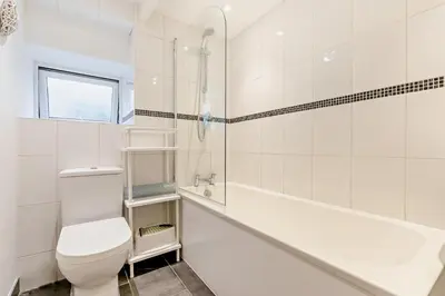a white bathroom with a toilet and a bath tub at 2 Bed in Wadebridge oc-r27444 in Little Petherick