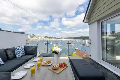 a living room with a table with food and a view of the water at 4 Bed in Polruan oc-scroft in Fowey