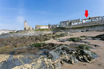 a view of a rocky beach with buildings in the background at 4 Bed in Porthleven oc-samcot in Porthleven