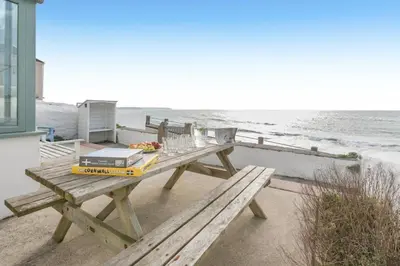 a picnic table with a laptop and glasses on the beach at 4 Bed in Porthleven oc-samcot in Porthleven